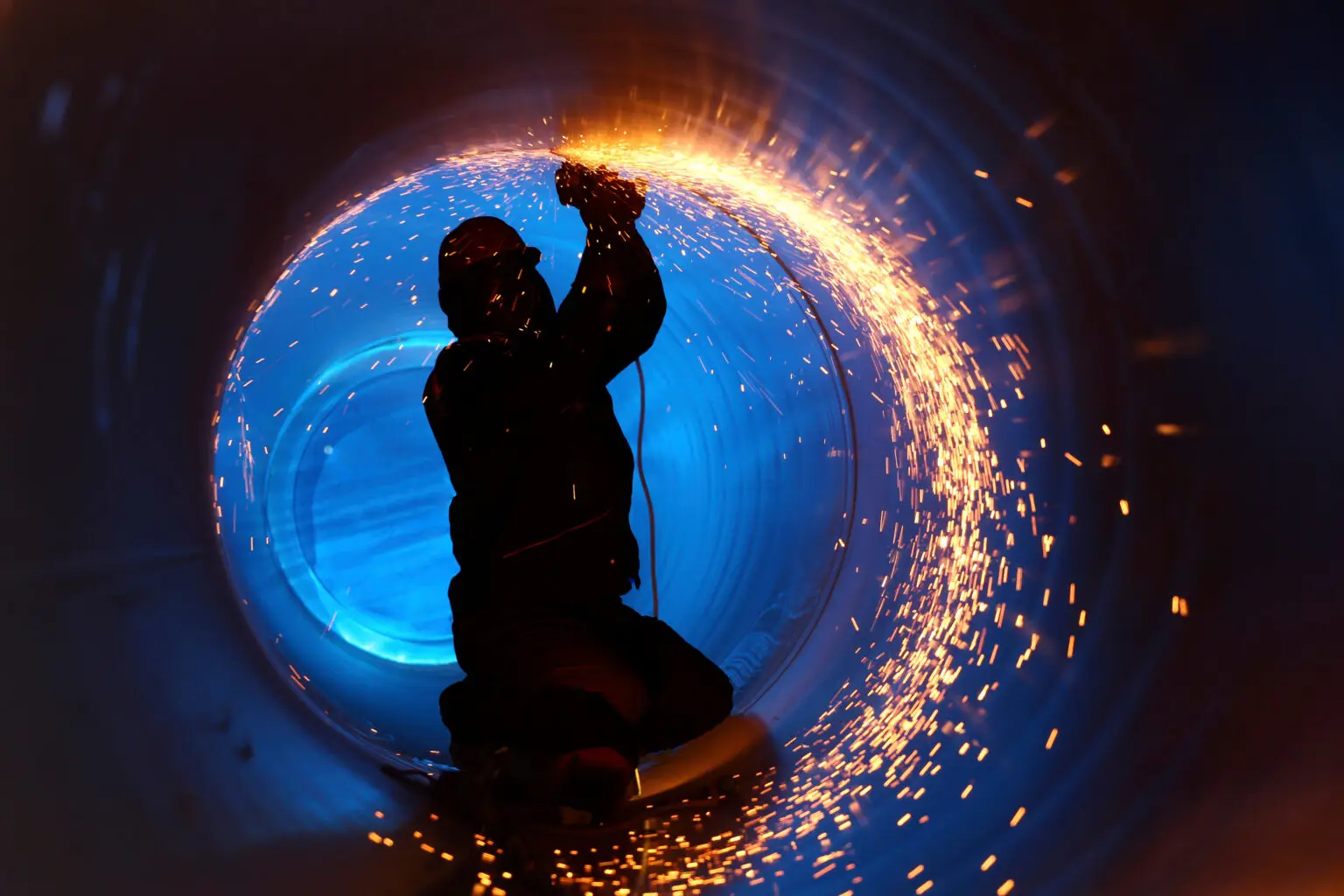 A worker works inside a pipe on a pipeline construction