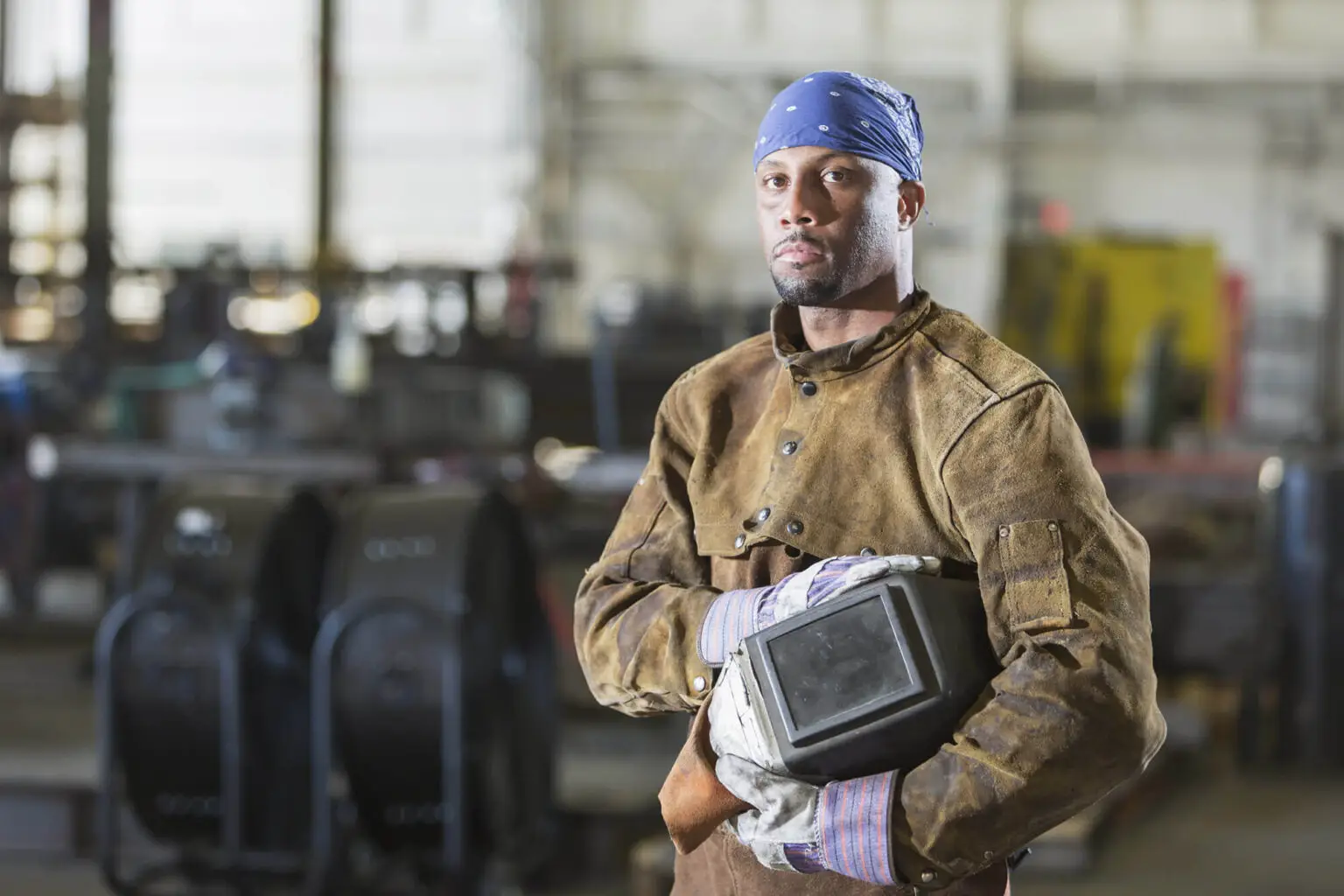 Welder holding welding helmet